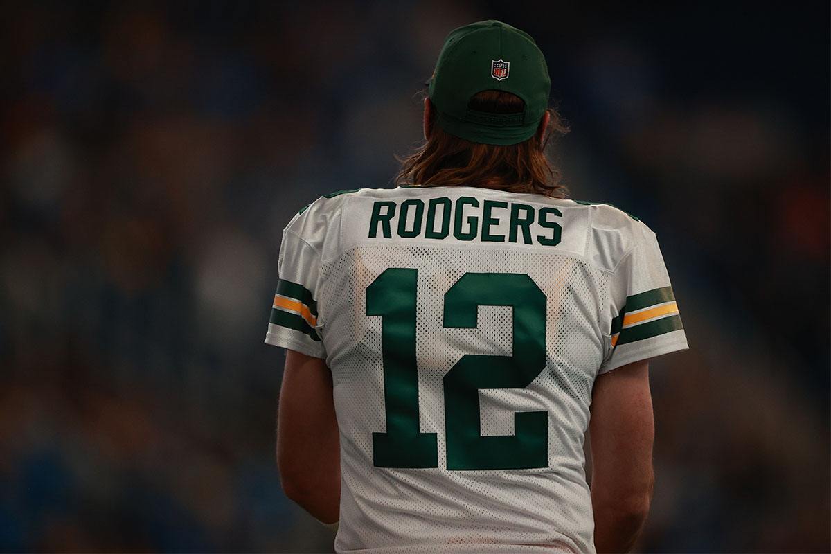 Aaron Rodgers walking on a football field.