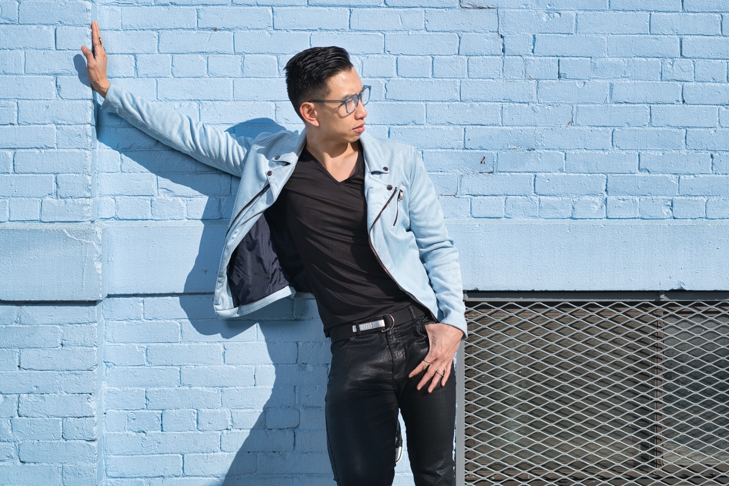 Sex Hacker Kenneth Play poses outdoors in front of a blue brick wall