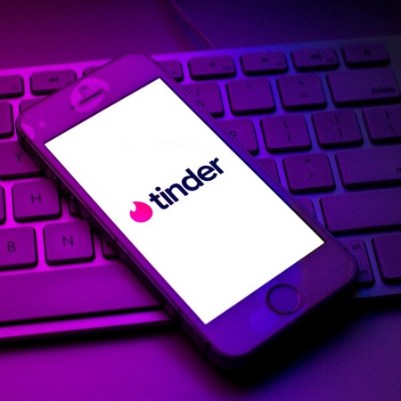 In this photo illustration a Tinder logo seen displayed on a smartphone on top of a computer keyboard.