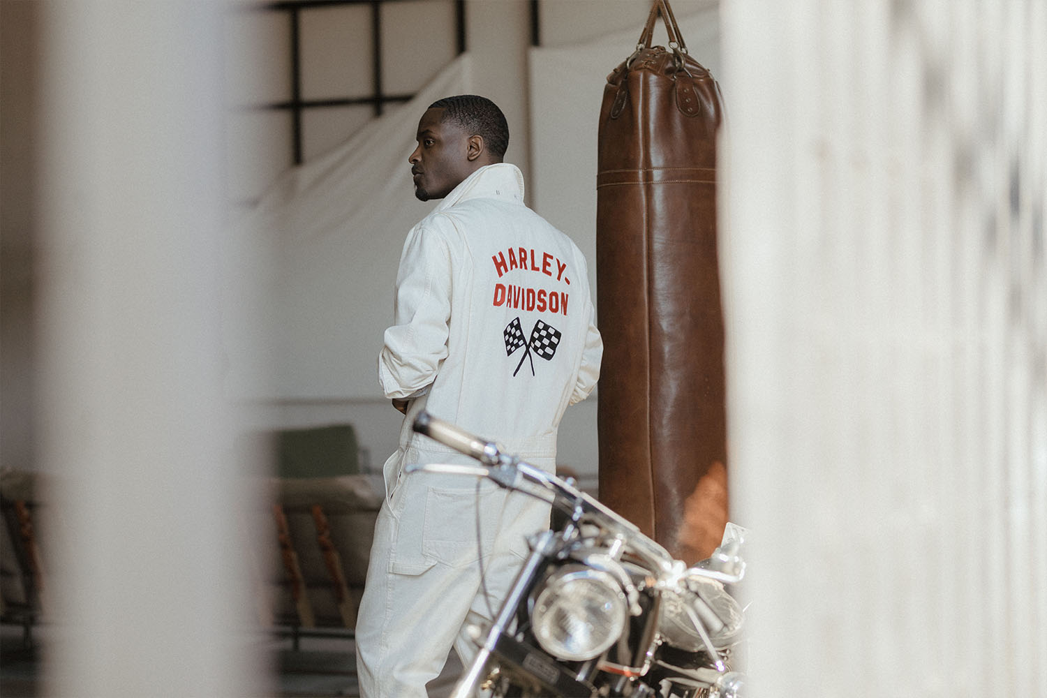 A model in Harley Davidson x Todd Snyder clothes standing by a motorcycle