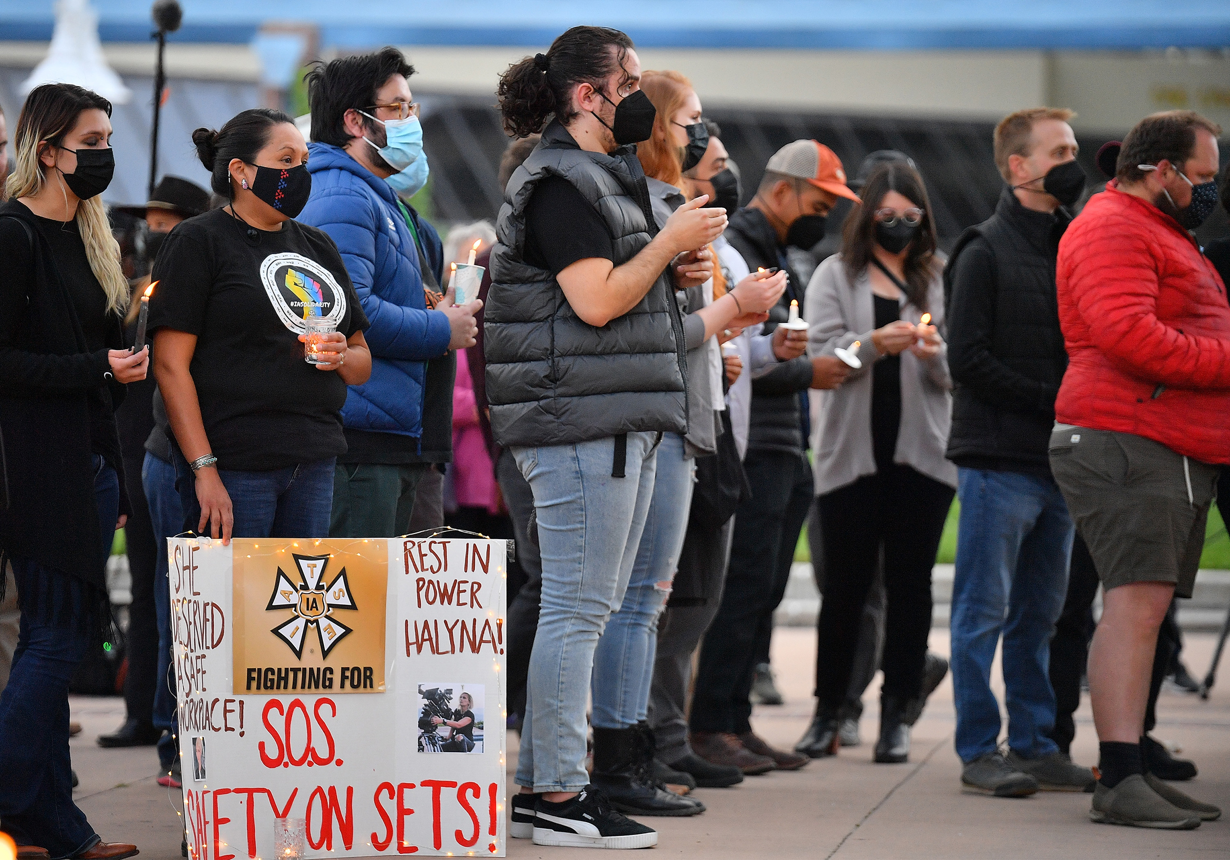 Production crew bear signs calling for better safety on sets at a vigil for cinematographer Halyna Hutchins, who was killed while filming the movie "Rust"