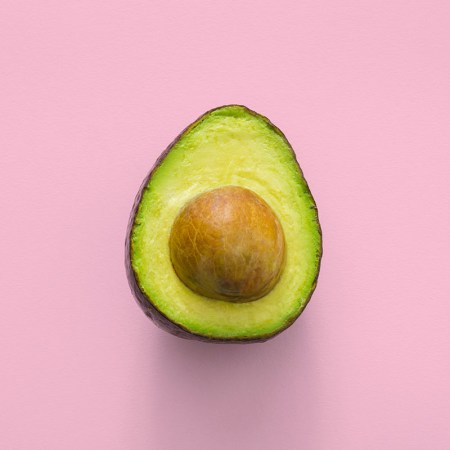 An avocado against a pink background.