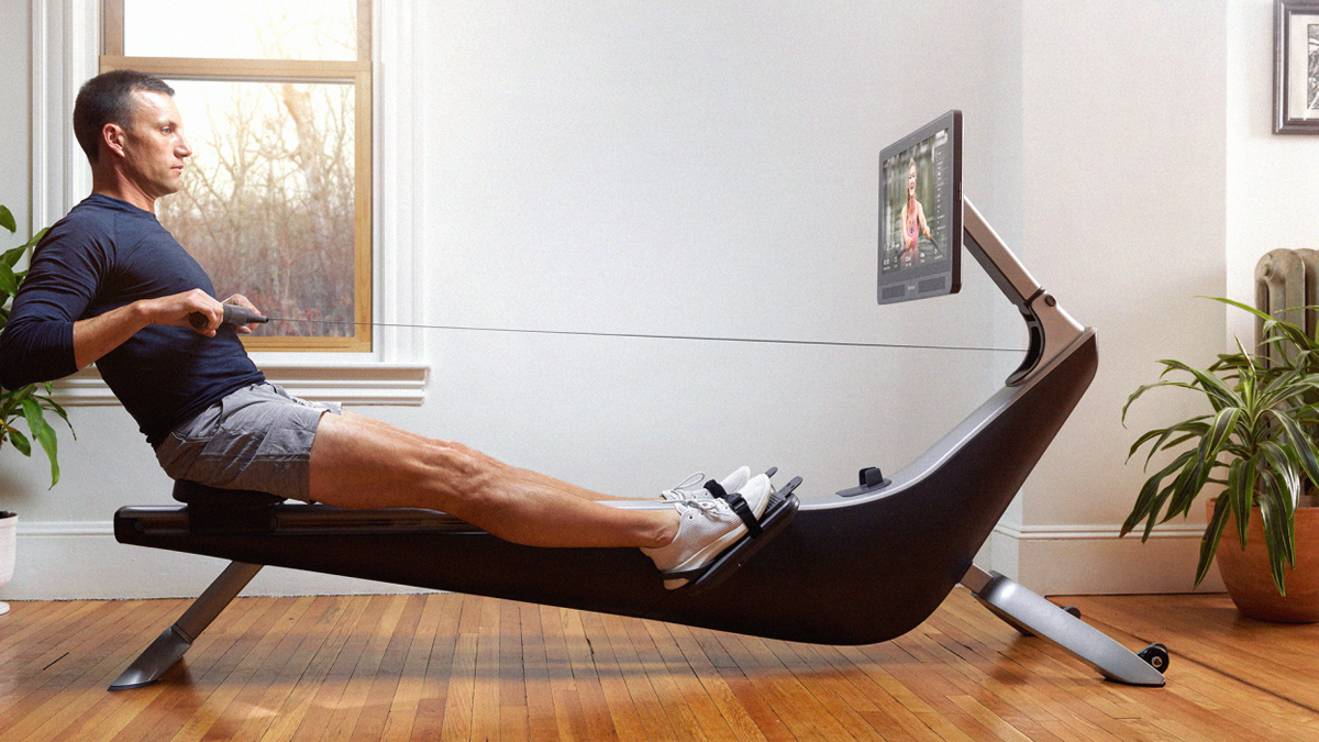 Man using Hyrow rowing machine in living room in 2022. They just opened a new flash sale — here's how to get a discount in March 2022.