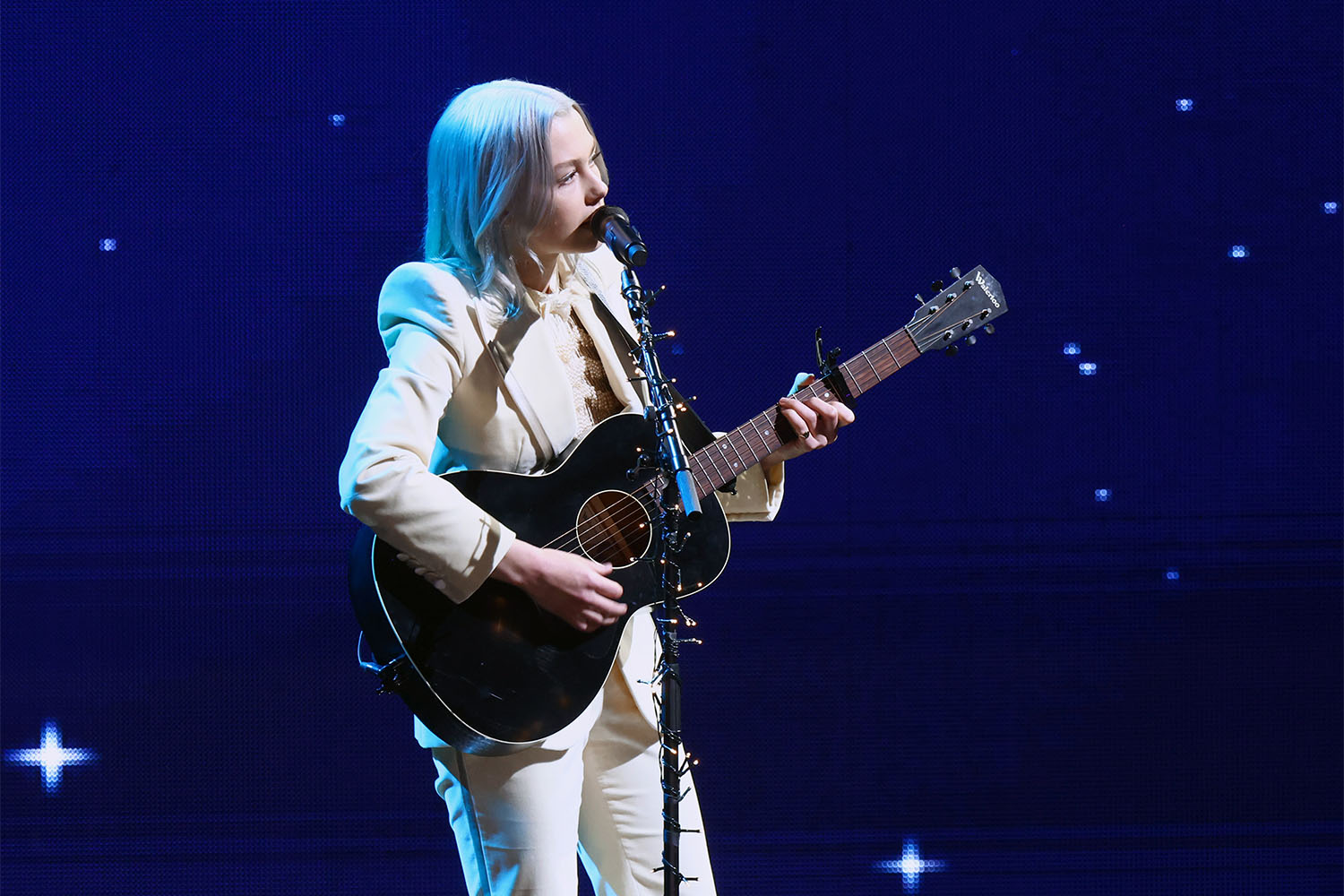 Musician Phoebe Bridgers preforming at the Billboard Women In Music Awards In a Gucci all-white power suit.