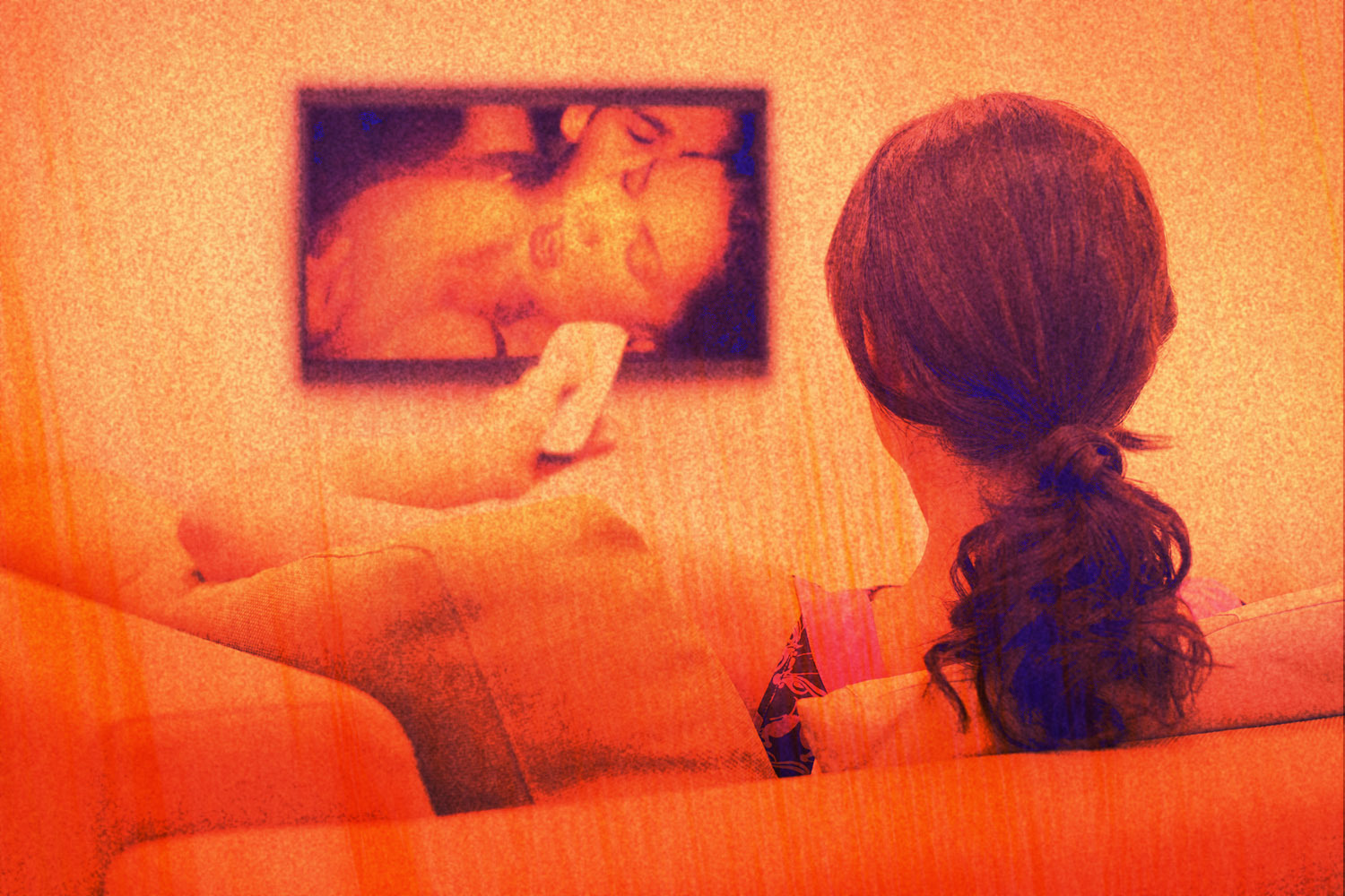 Image shows a woman sitting on the couch watching porn on TV