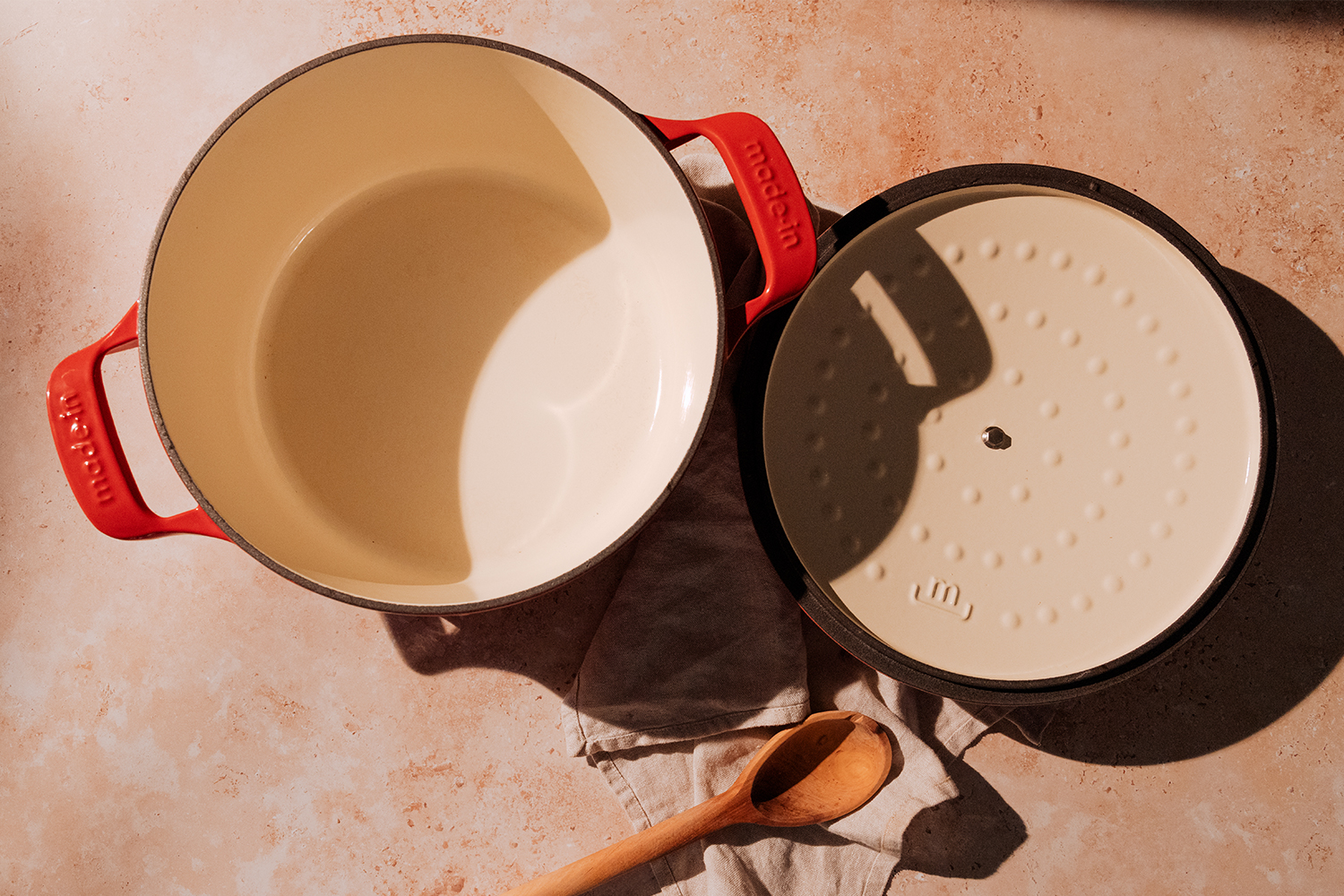 The interior of the red Dutch oven from Made In. The lid is also flipped upside down to show the bumps that are supposed to distribute moisture evenly.