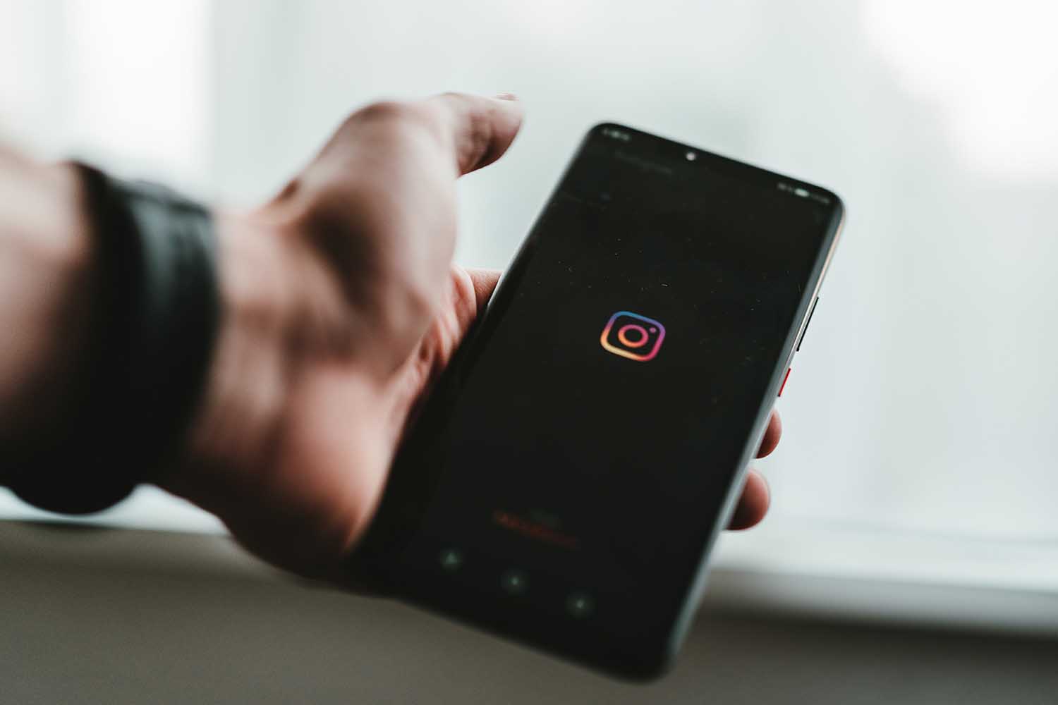 A person holding a phone displaying the Instagram icon.