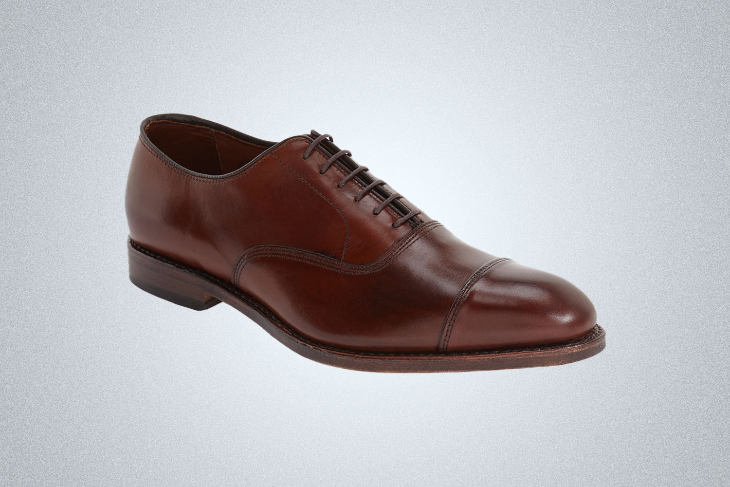 a pair of Allen Edmonds dark brown leather oxfords on a grey background