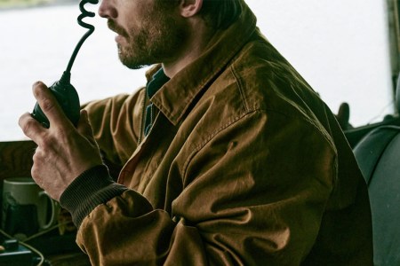 A model wearing a Filson Aberdeen Jacket driving a truck.