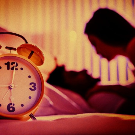 A shadowy image of a couple having sex in the background, a clock in the foreground.