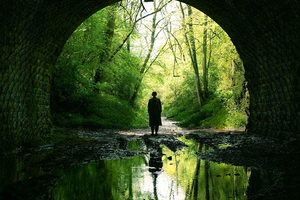 A woman entering a dark tunnel, a scene from the new Alex Garland horror film "Men." It's one of our favorite movies coming out in May 2022.