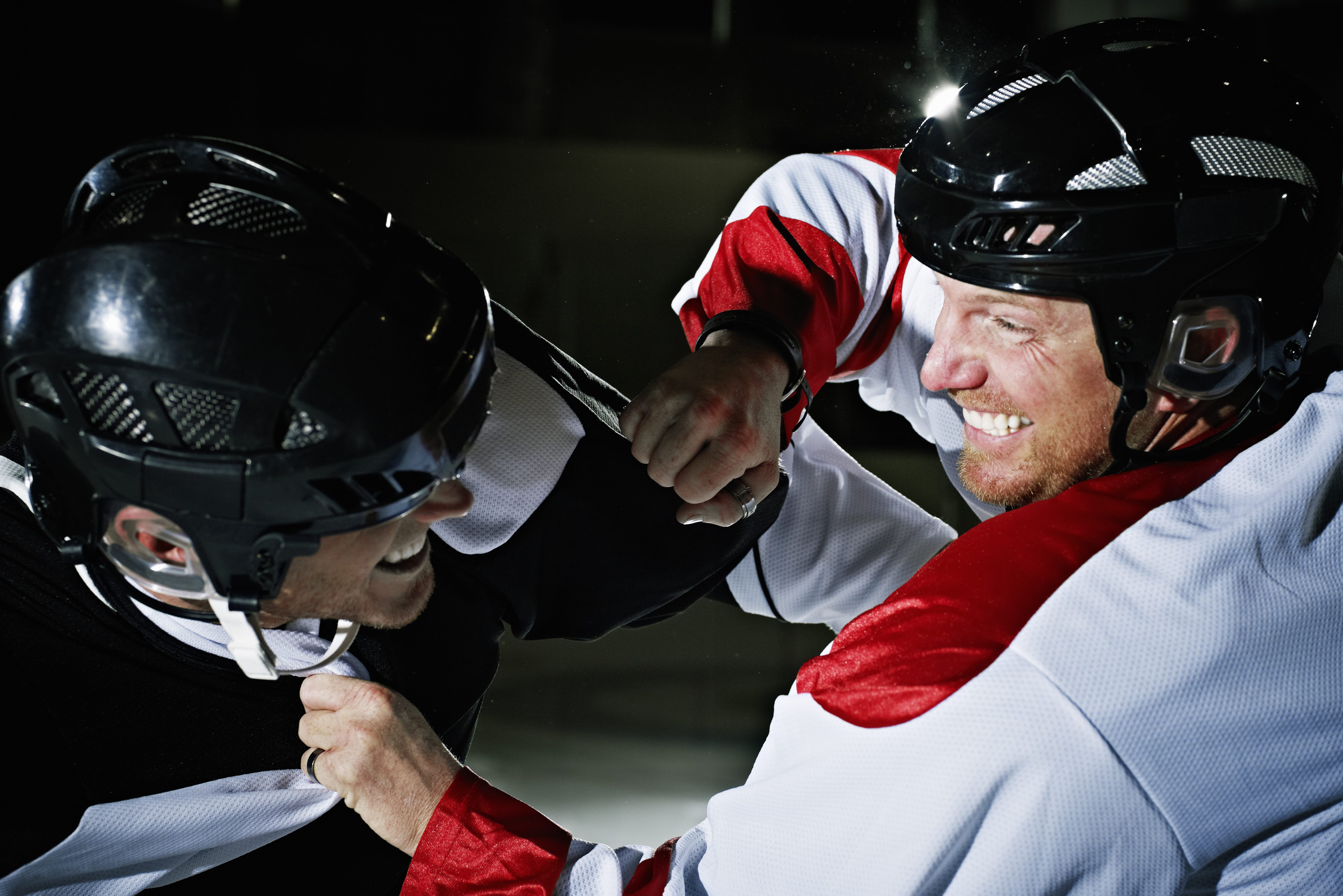 Two hockey players from opposing teams fighting on the ice.