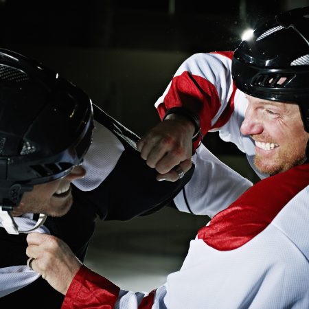 Two hockey players from opposing teams fighting on the ice.