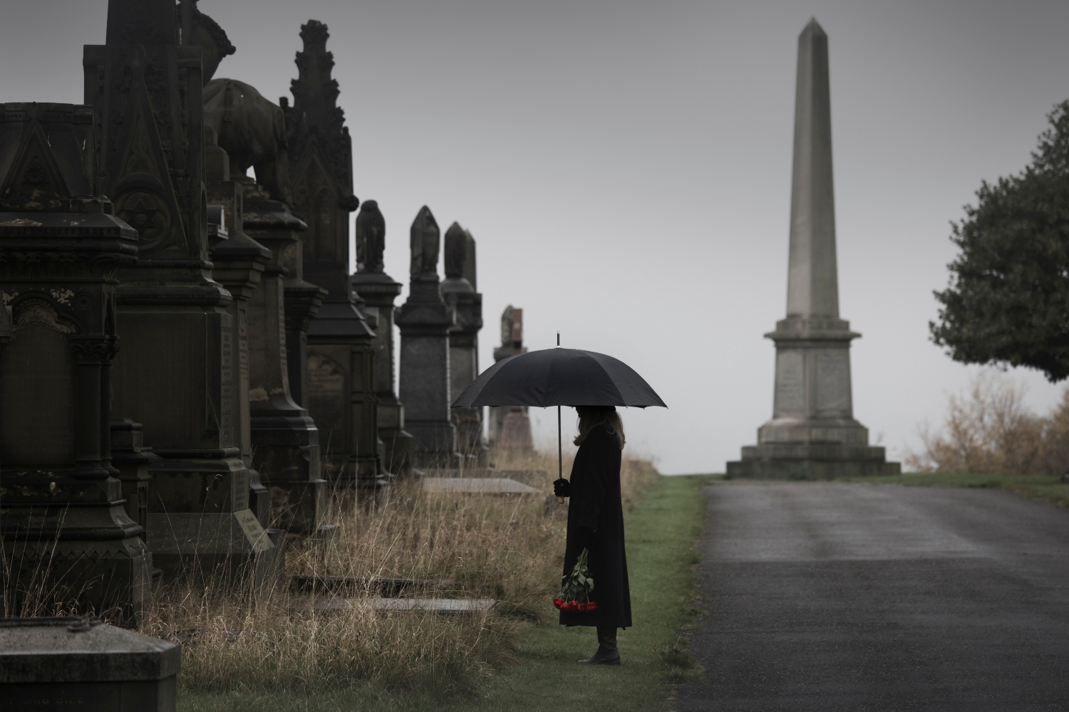 widow bringing roses to a grave in a cemetery