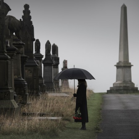 widow bringing roses to a grave in a cemetery