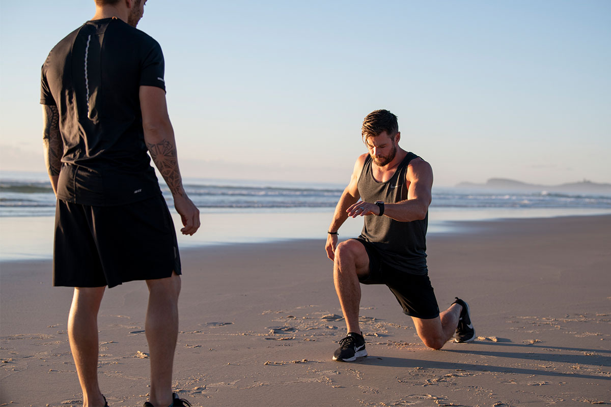 Chris Hemsworth performing a lunge on the beach.