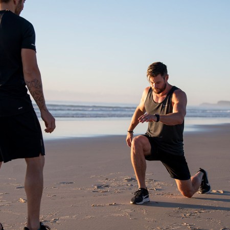 Chris Hemsworth performing a lunge on the beach.