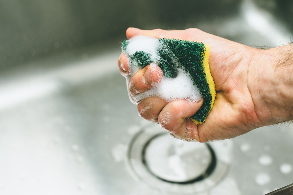 A man holding a kitchen sponge.