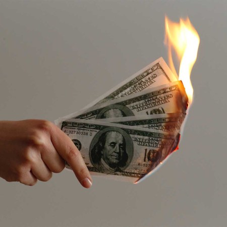 Hand holding money on fire