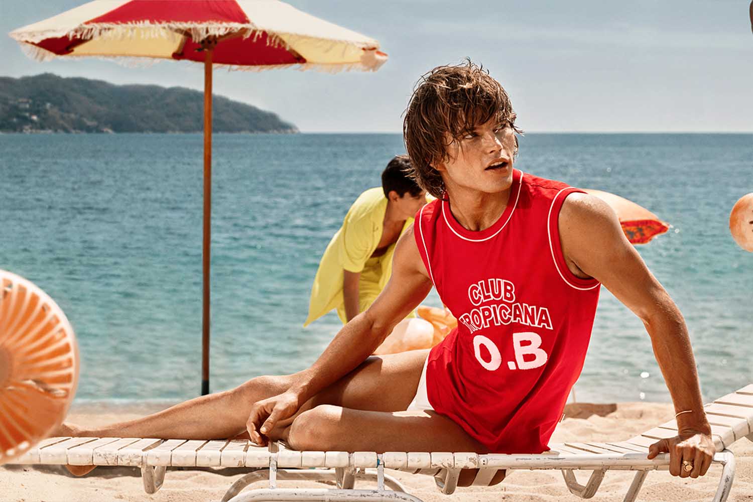 A model lounging on a pool chair by the beach