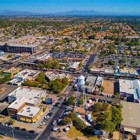 Aerial View of the Phoenix suburb of Gilbert, AZ with Downtown Gilbert in the foreground and residential areas and mountains in the background.