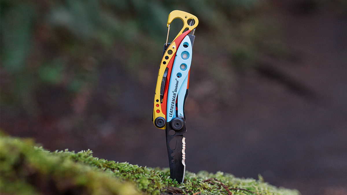 The Leatherman x Topo Designs Skeletool sticking into a log with the knife down. The multitool may be the best-looking Leatherman ever made.