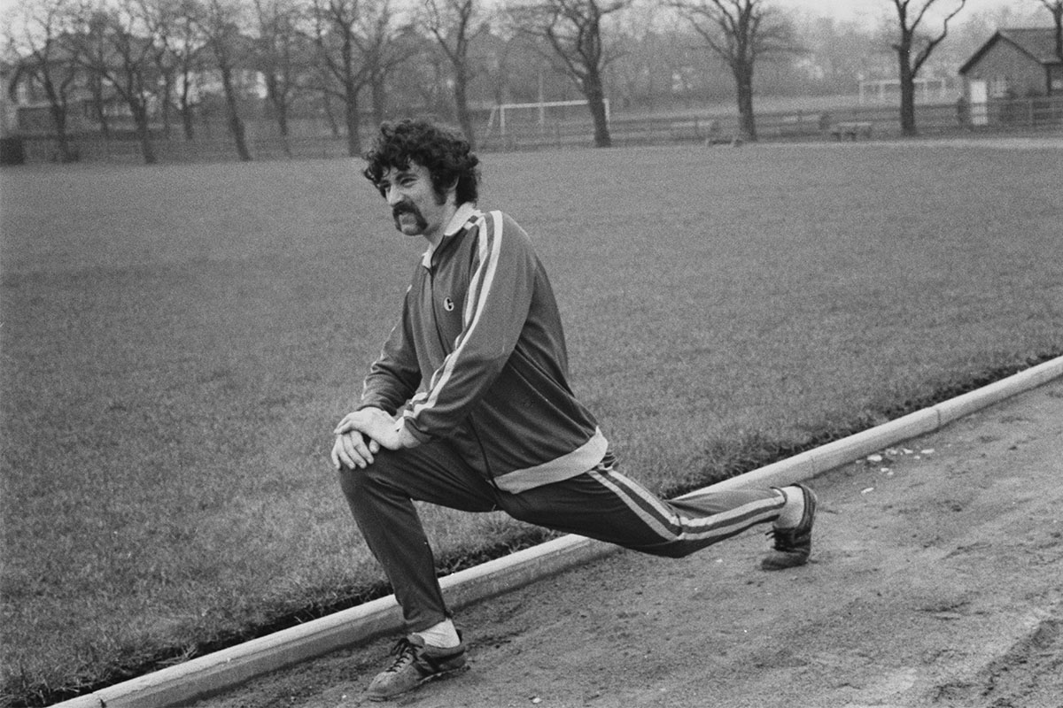 A man stretching on a track in black and white. Here's how you can bulletproof your body.