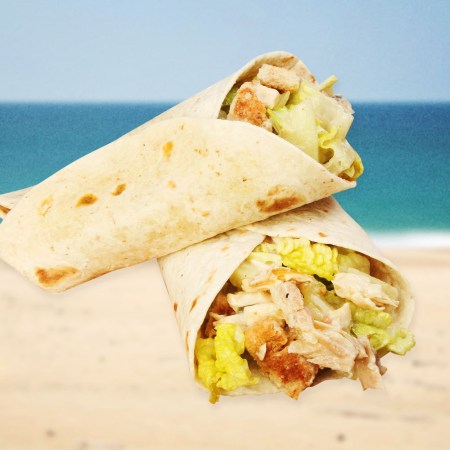 A Caesar salad wrap floating in front of a coastline.