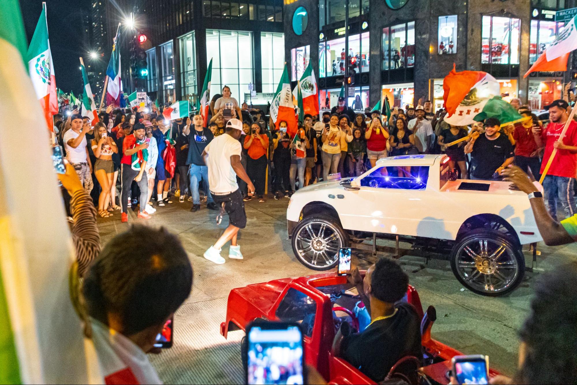 A crowd of people celebrating Mexican Independence Day in Chicago's Loop, with a man dancing in the middle next to a small truck