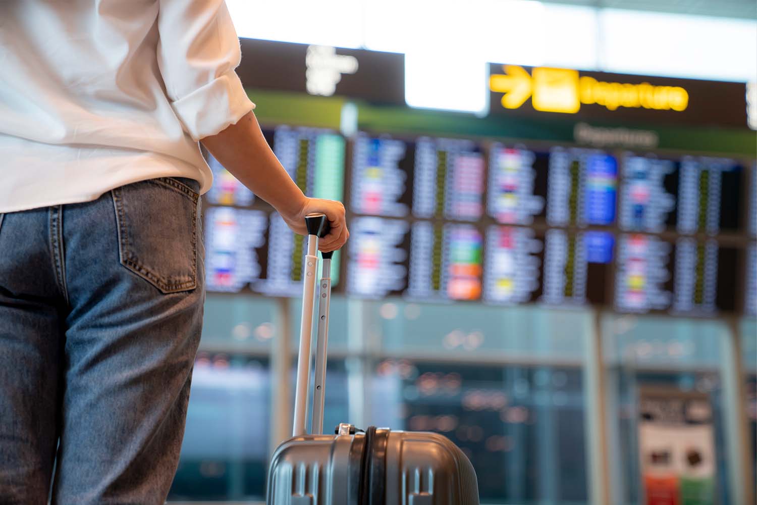 Traveler standing in front of a flight display schedule in an international airport