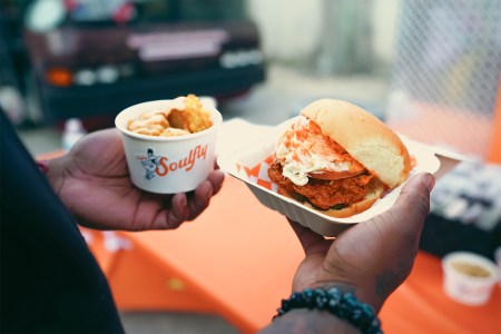 A fried chicken sandwich and sides from Soulfly Chicken being held in two hands