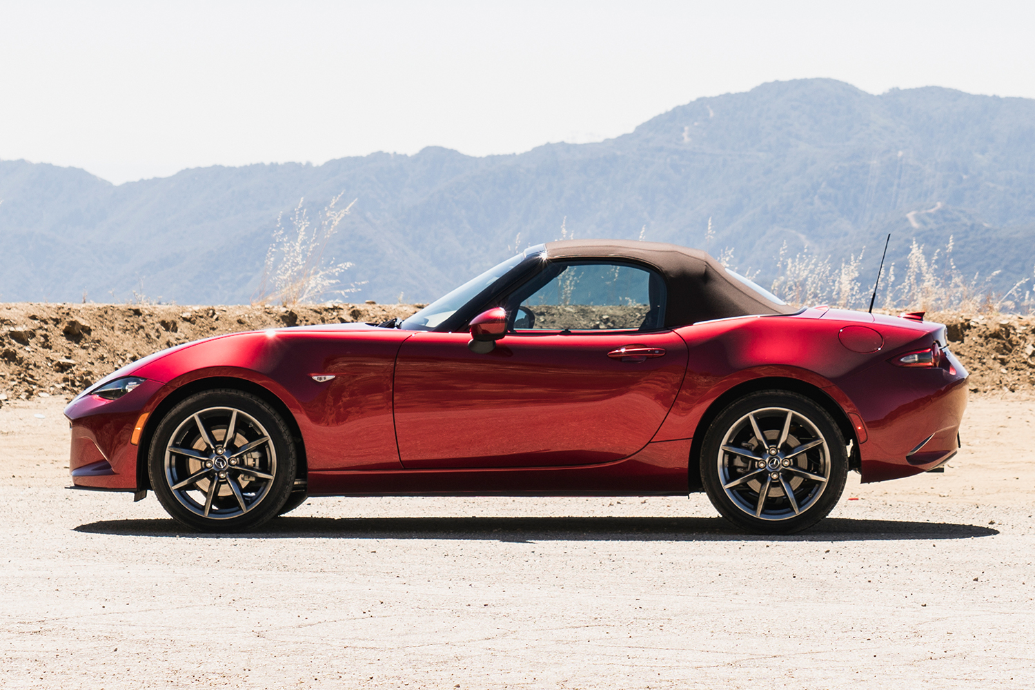 A red Mazda MX-5 Miata sitting in the desert and shot in side profile