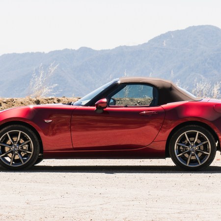 A red Mazda MX-5 Miata sitting in the desert and shot in side profile