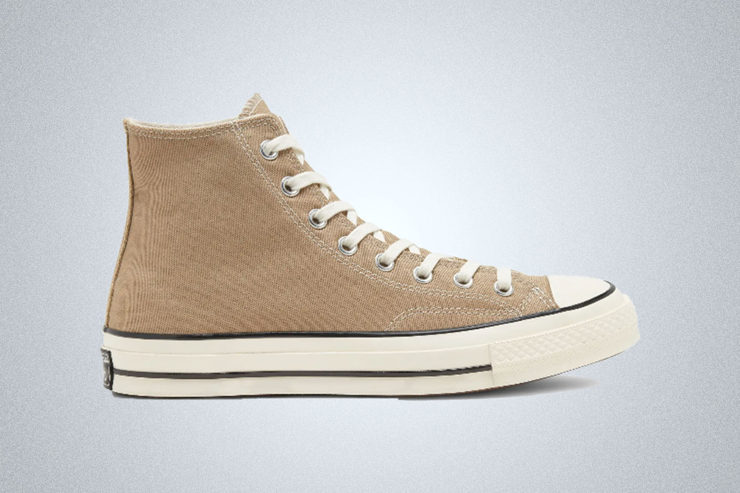 A pair of tan Chuck Taylor Converse sneakers on a grey background