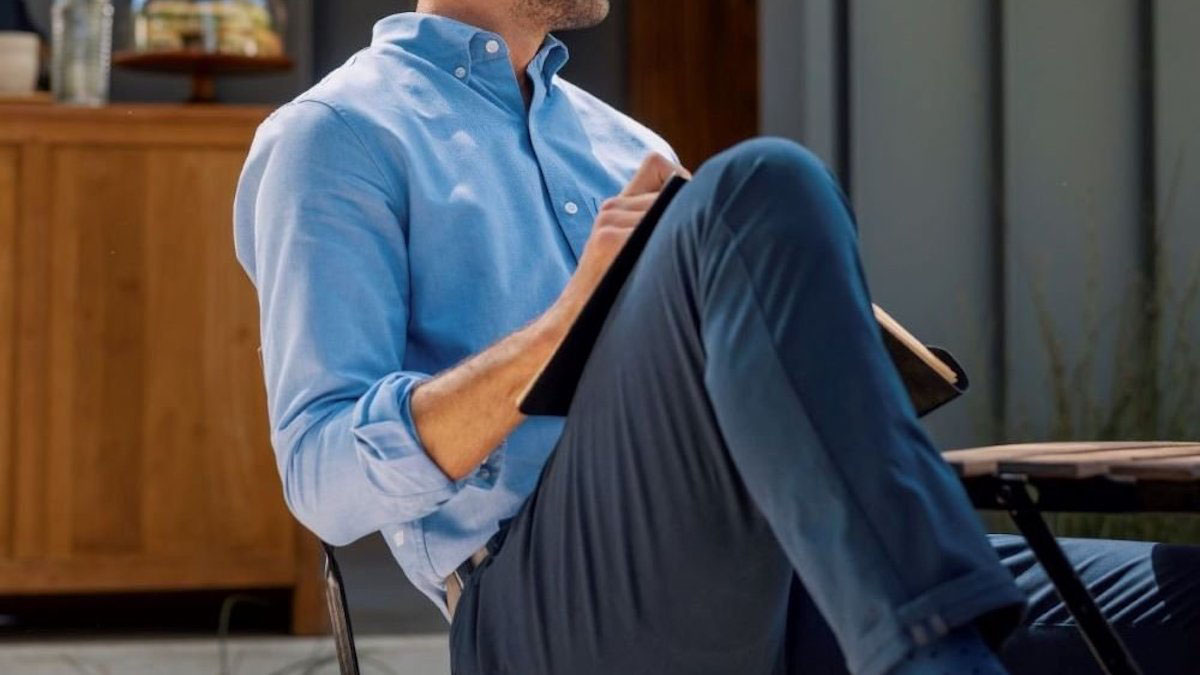 a model in Mack Weldon cloths sitting and writing outside in a chair