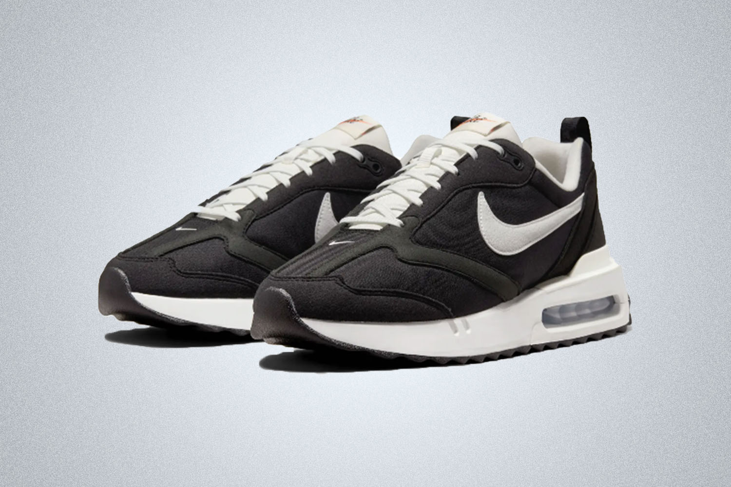 A pair of black and white Nike Air Max sneakers on a grey background