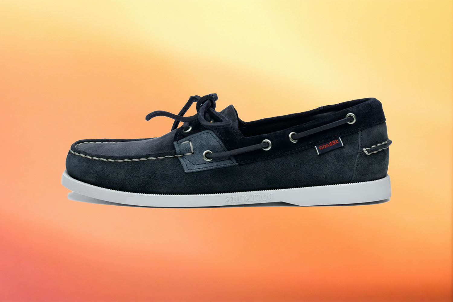 a navy blue Sebago boat shoe on a yellow-orange gradient background