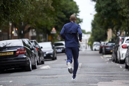 A model in Tracksmith clothing running in the middle of a street