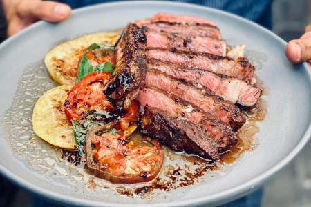 A porterhouse steak with tomatoes and balsamic vinegar from Chef Neal Fraser of Redbird, made at his annual Beefsteak event in 2022