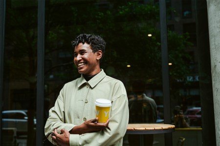 Ayat Elhag, coffee director of the Yellow cafe in Washington, DC, stands with her arms crossed and holding a yellow coffee cup