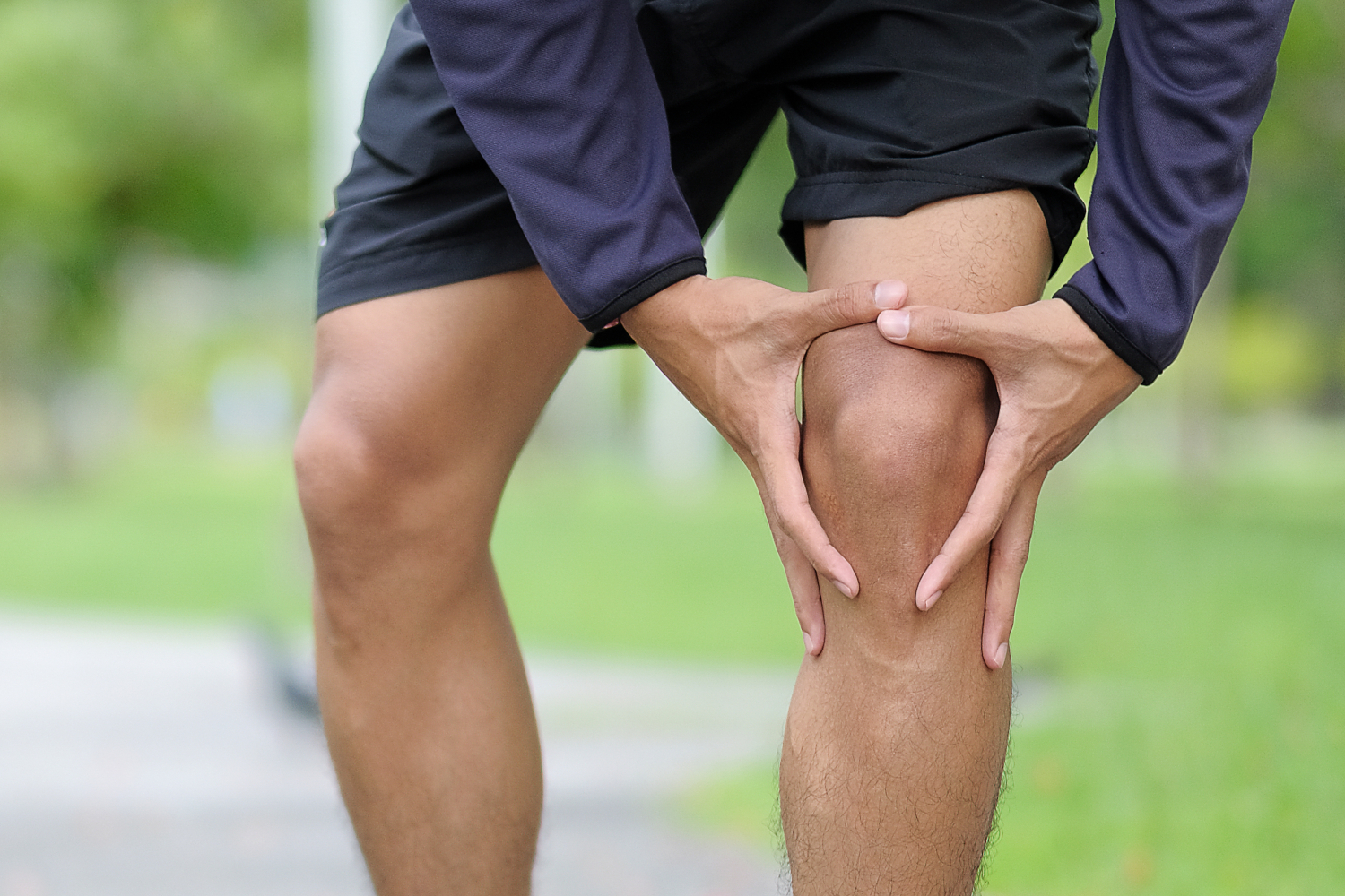 Young man outside holding his bare knee