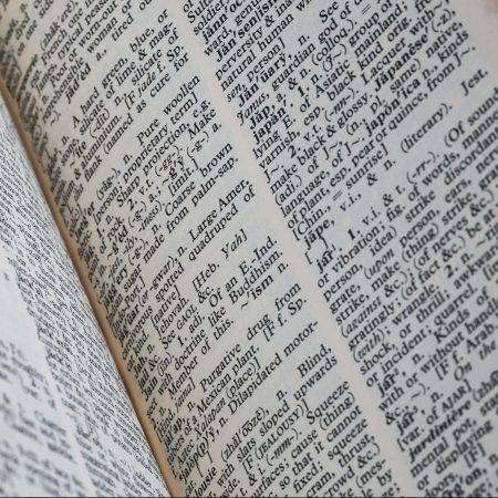 A very old dictionary with torn pages against a white background.