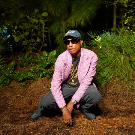 Pharrell crouching in a woodland setting for a photo shoot.