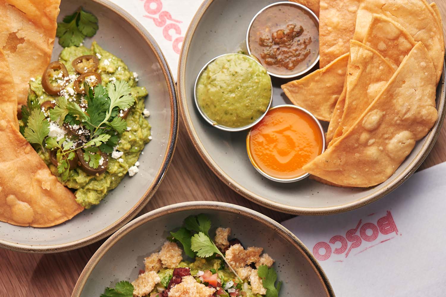 A spread of chips and various salsas, chips and guac and a salad