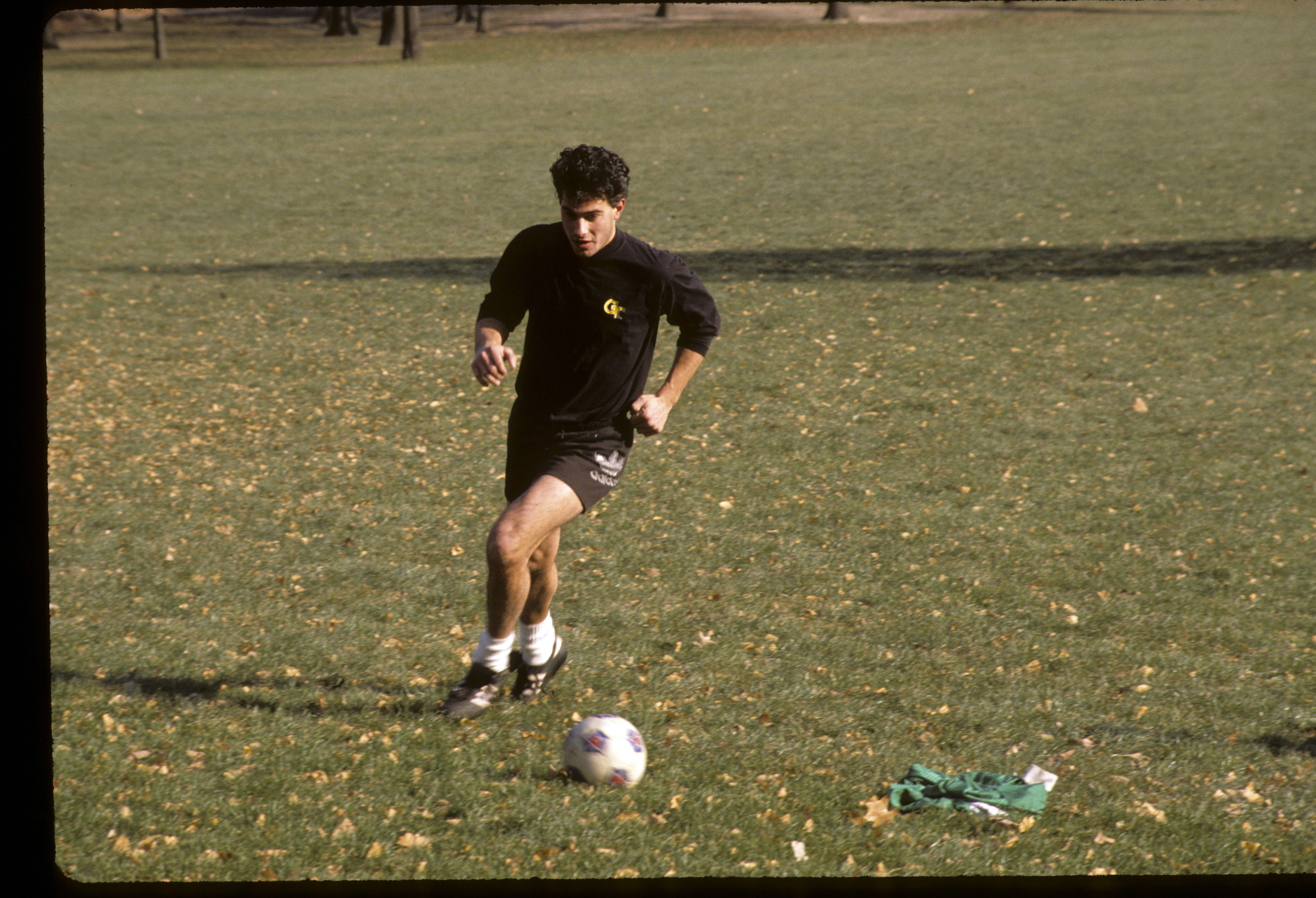 A young man dribbles a soccer ball on a patch of grass in Central Park.