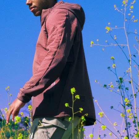 A photograph of a model in Lululemon Hike clothing standing in a grassy field against a blue sky