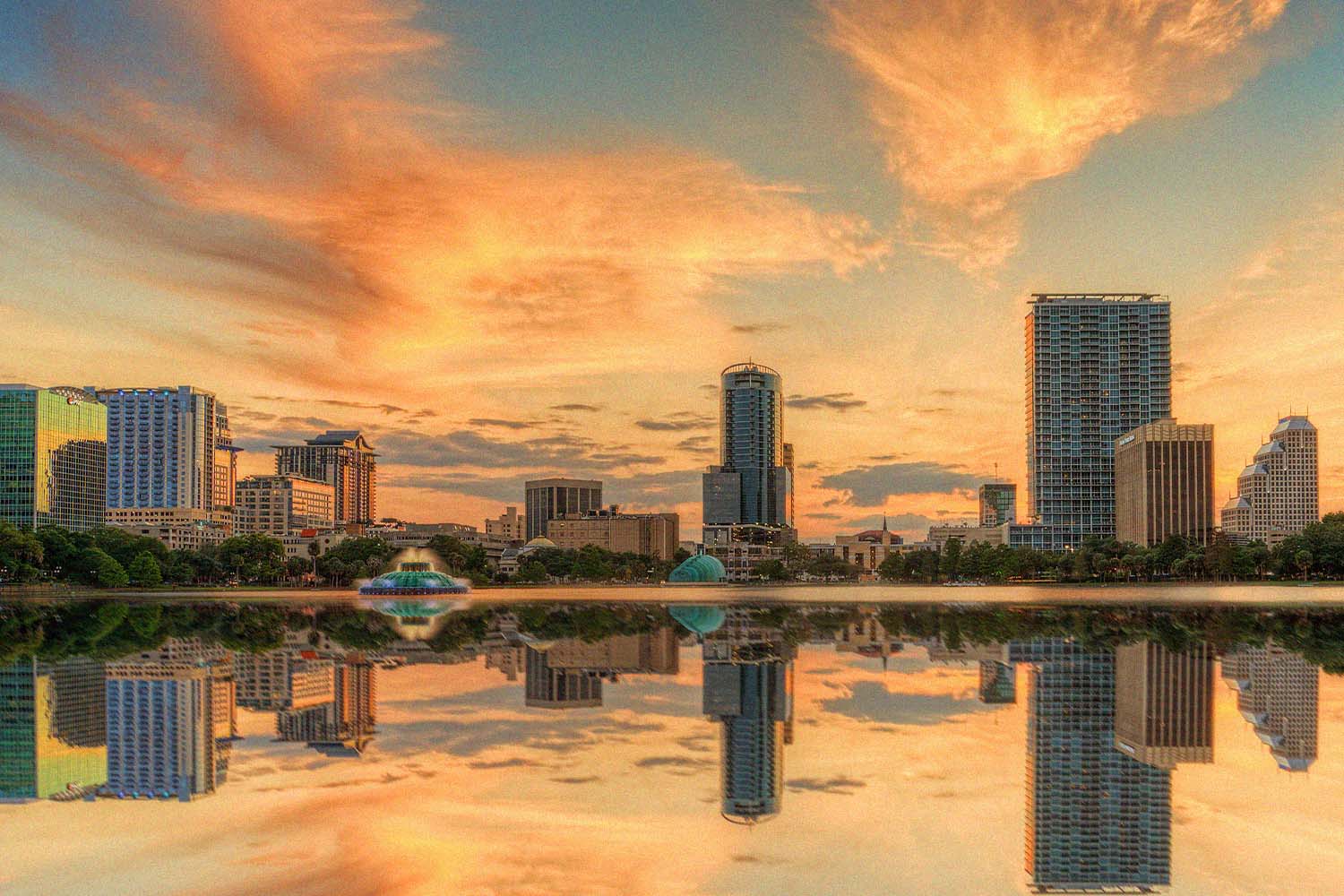 A colorful sunset over Lake Eola and Orlando, Florida with reflections captured off the lake.