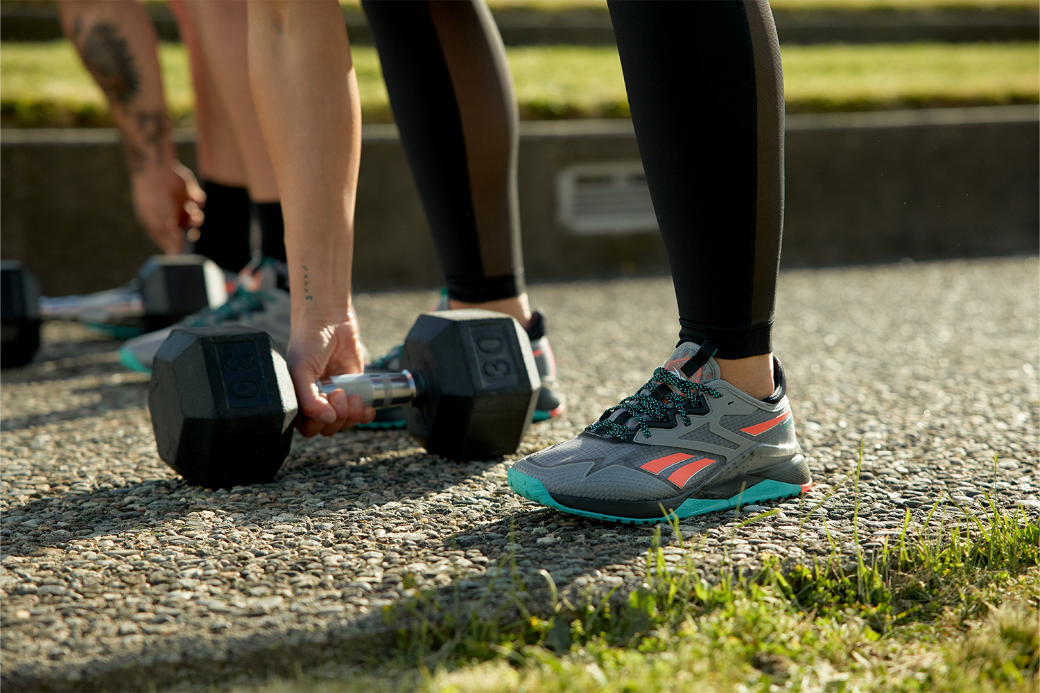 a model lifiting a weight outdoors wearing the Reebok Nano Adventure 2