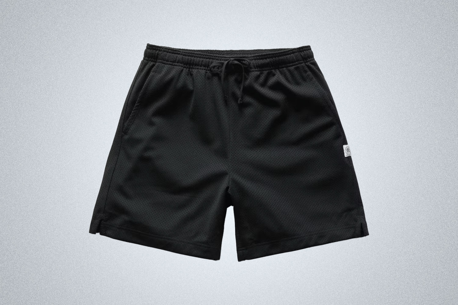 a pair of black mesh shorts from Reigning Champ on a grey background