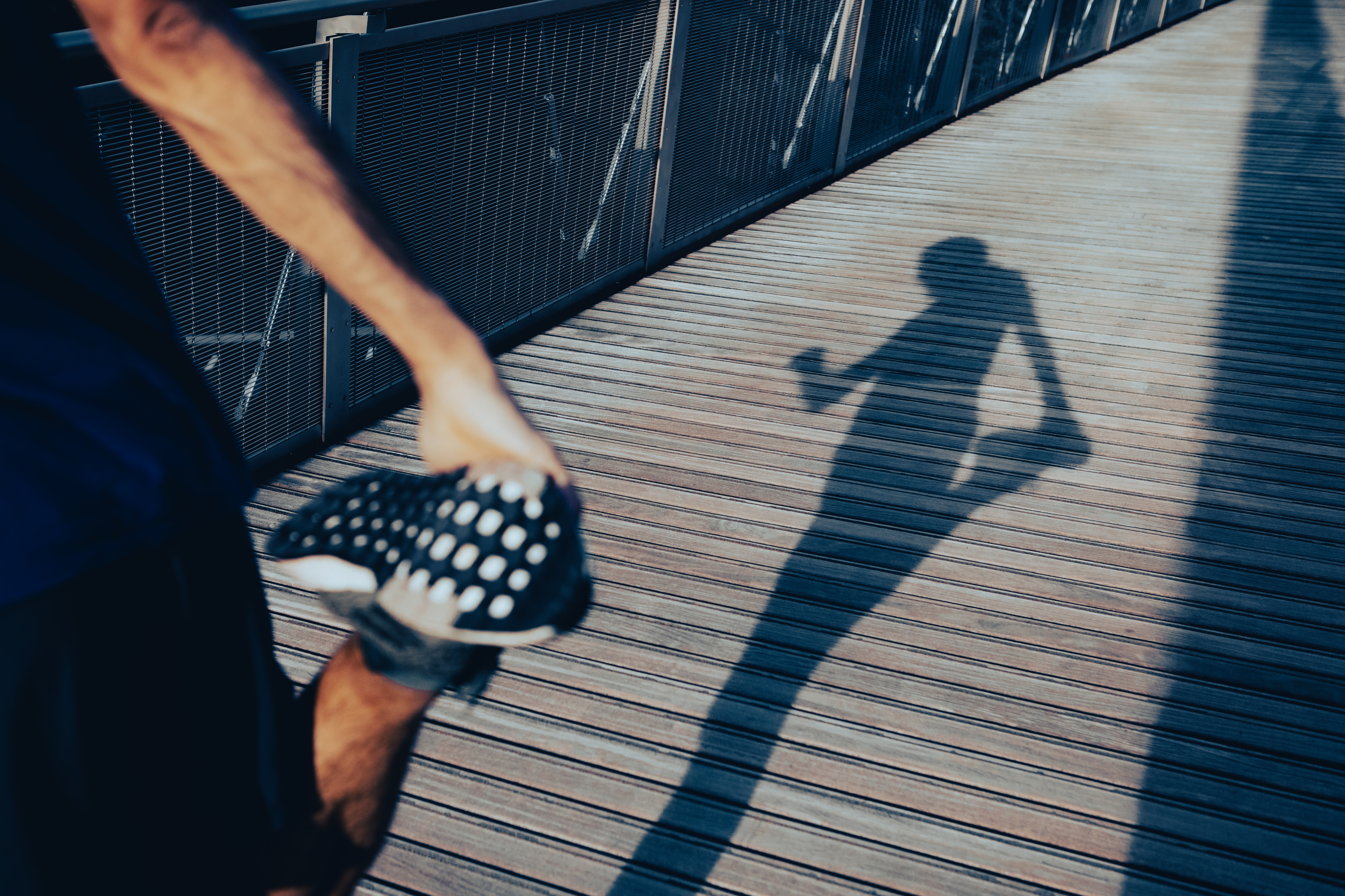 The shadow of a runner holding onto his foot to stretch before a run.